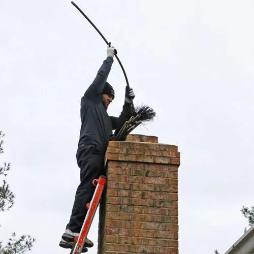 Chimney sweep feeding a rotary brush into a masonry chimney
