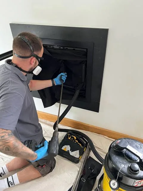 Technician examining an accessible fireplace flue with cleaning equipment